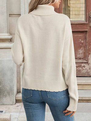 Ivory turtleneck cable-knit sweater with geometric pattern detail and ribbed trim.