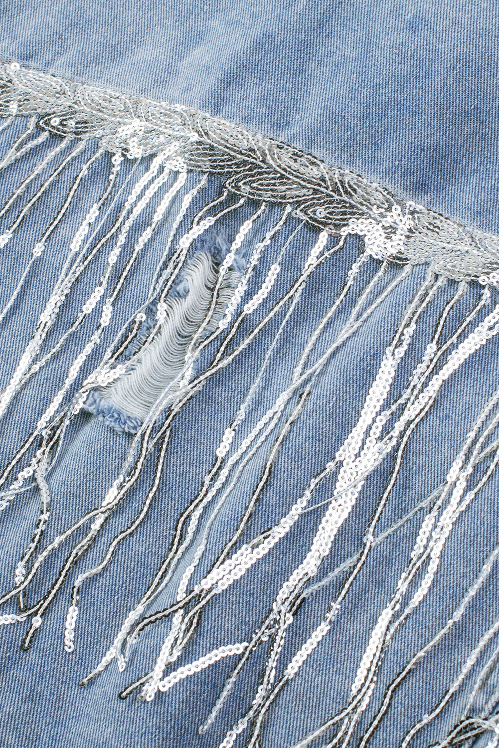 Denim trucker jacket with sequin fringe detail and distressed accents.