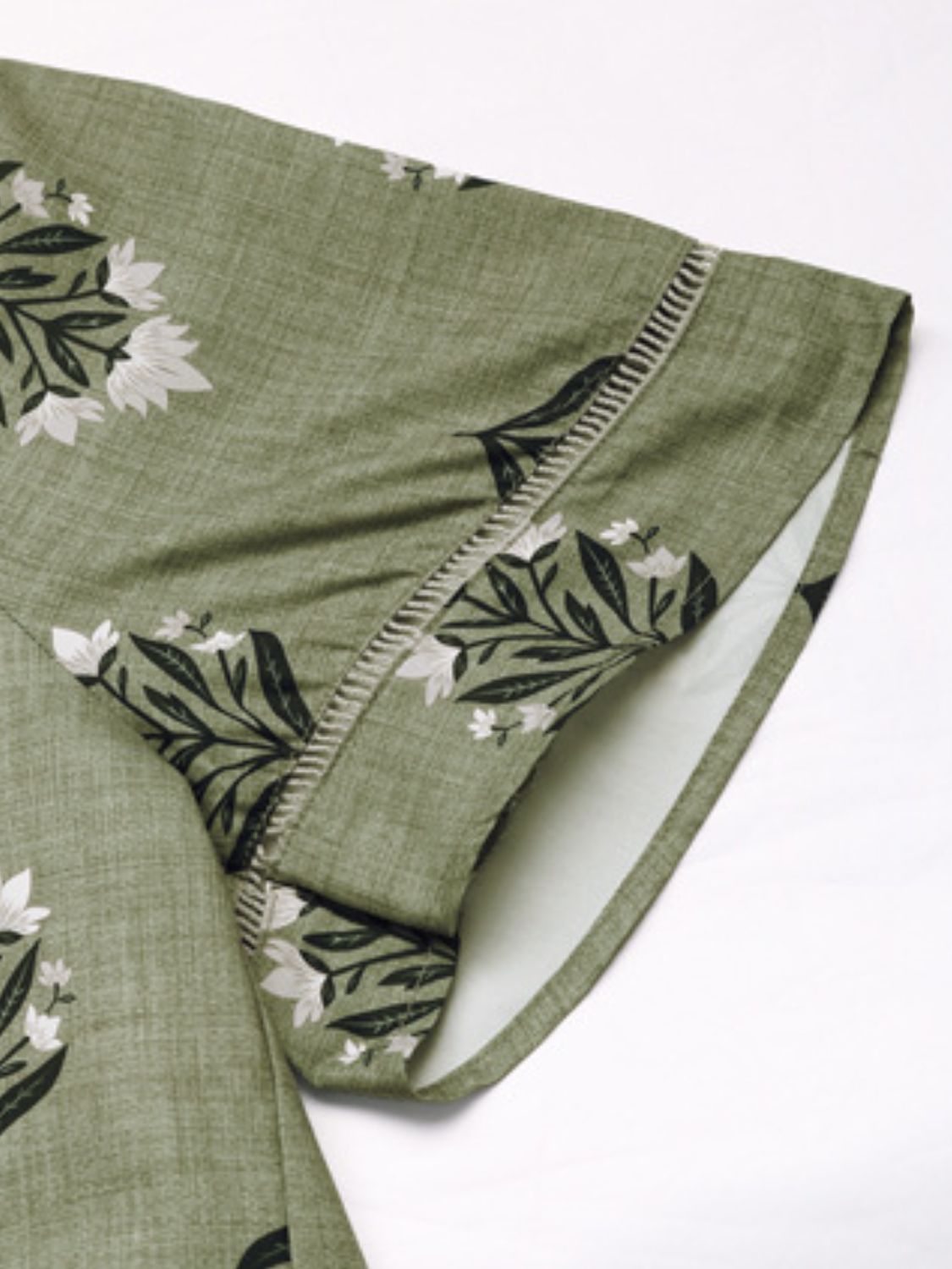 Botanical print blouse in matcha green with short sleeves and decorative stitching detail.