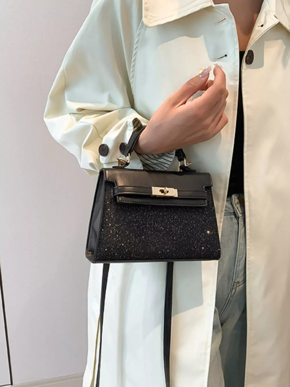 Black glitter textured mini crossbody bag with gold hardware and turn-lock closure.