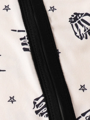Beige baby one-piece with black skeleton hand and star print and black trim.