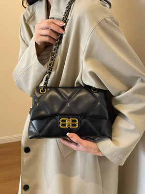 Black quilted flap chain shoulder bag with gold hardware and logo clasp