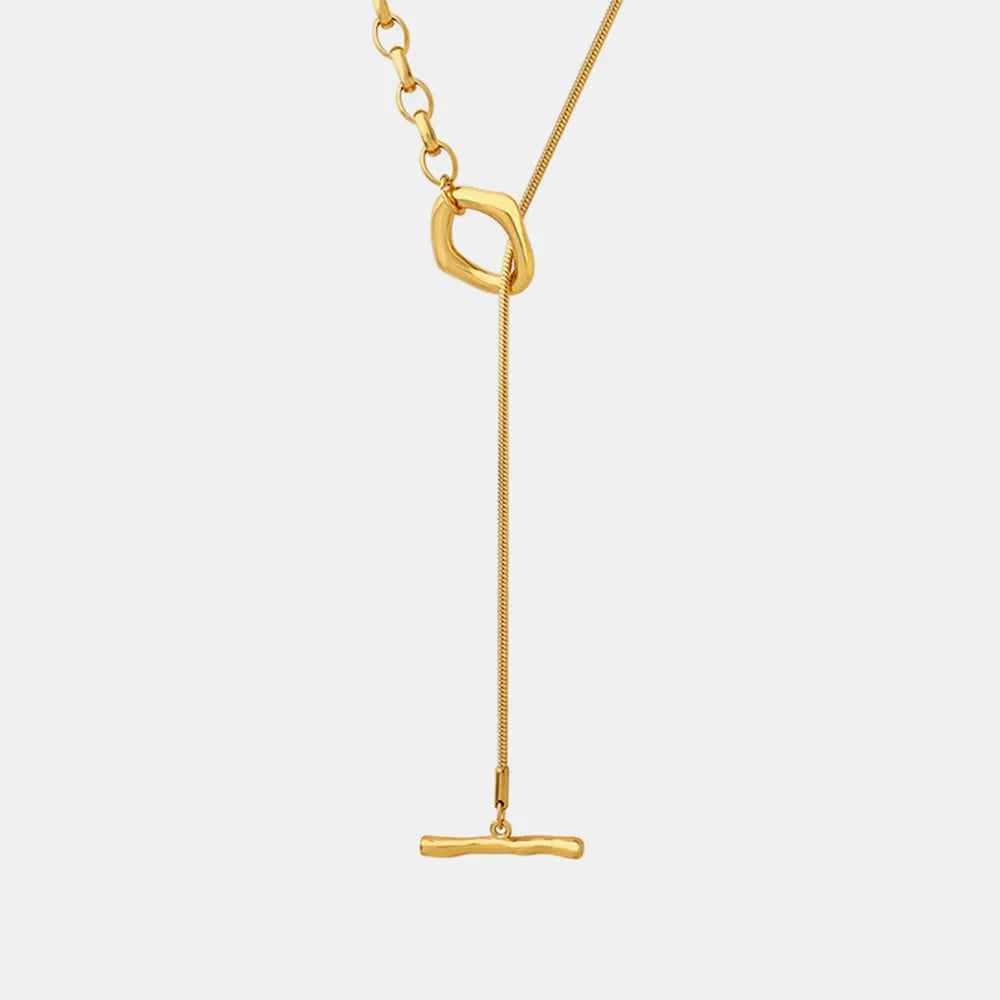 Gold asymmetrical chain necklace with a bar pendant and abstract link detail.