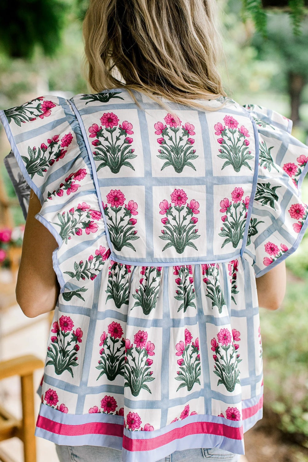 Women's ruffle sleeve blouse with floral print and blue checkered pattern.