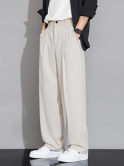 Men's beige wide-leg chinos with pleats and pockets, styled with a black jacket and white sneakers.