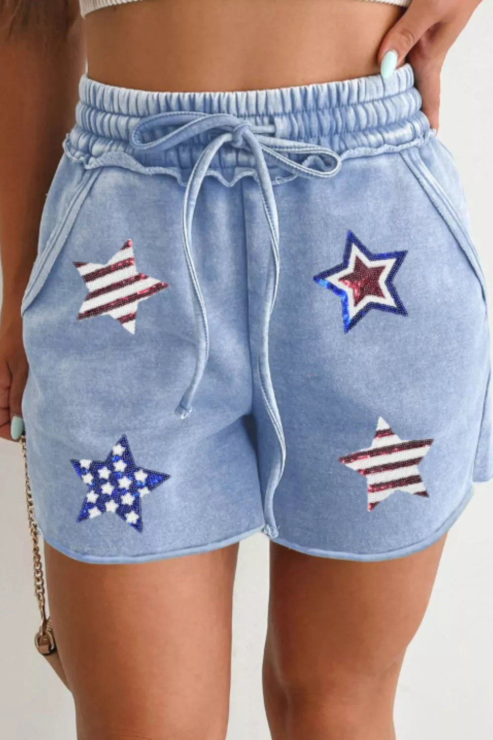 Light blue cotton drawstring shorts with sequined stars pattern.