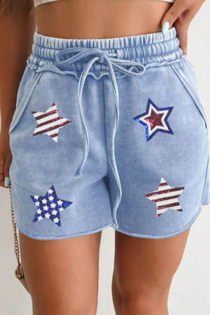 Light blue cotton drawstring shorts with sequined stars pattern.