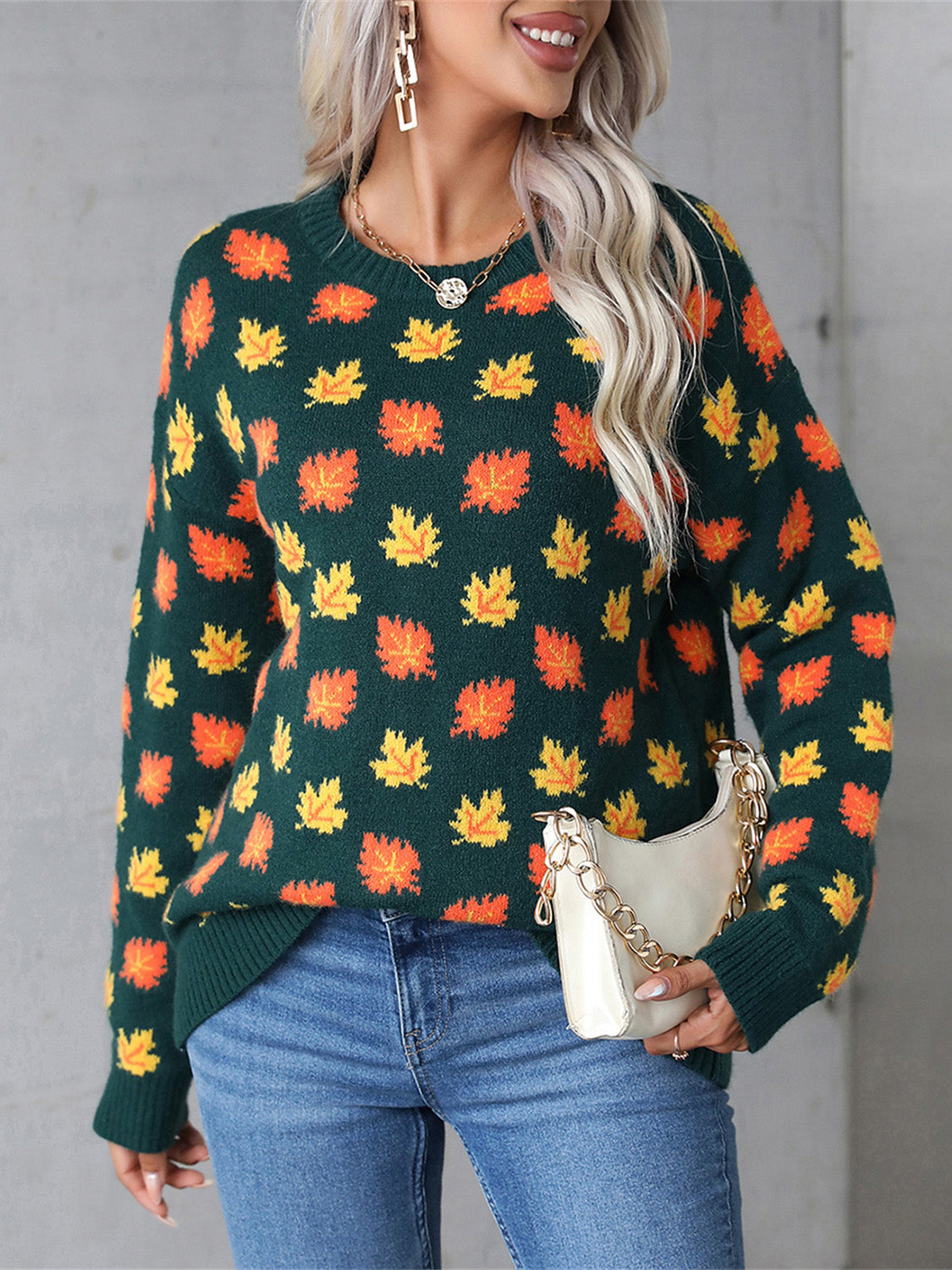 Dark green acrylic crewneck sweater with all-over orange and yellow leaf print.
