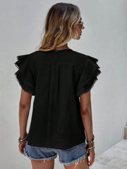 Black blouse with ruffle sleeves and pom-pom trim, back view.