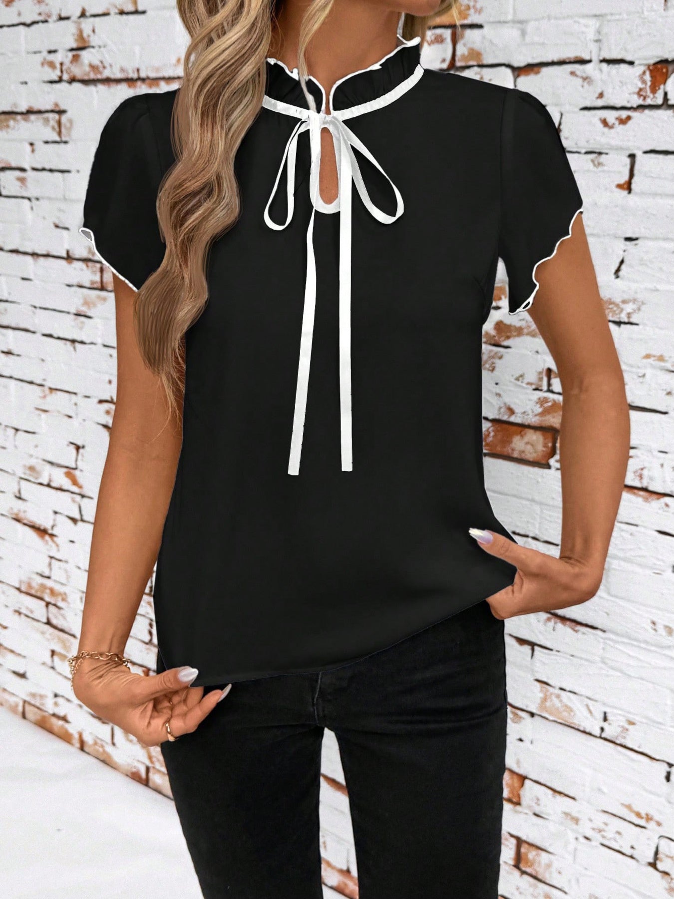 Black maternity blouse with frilled tie-neck and white trim detail.