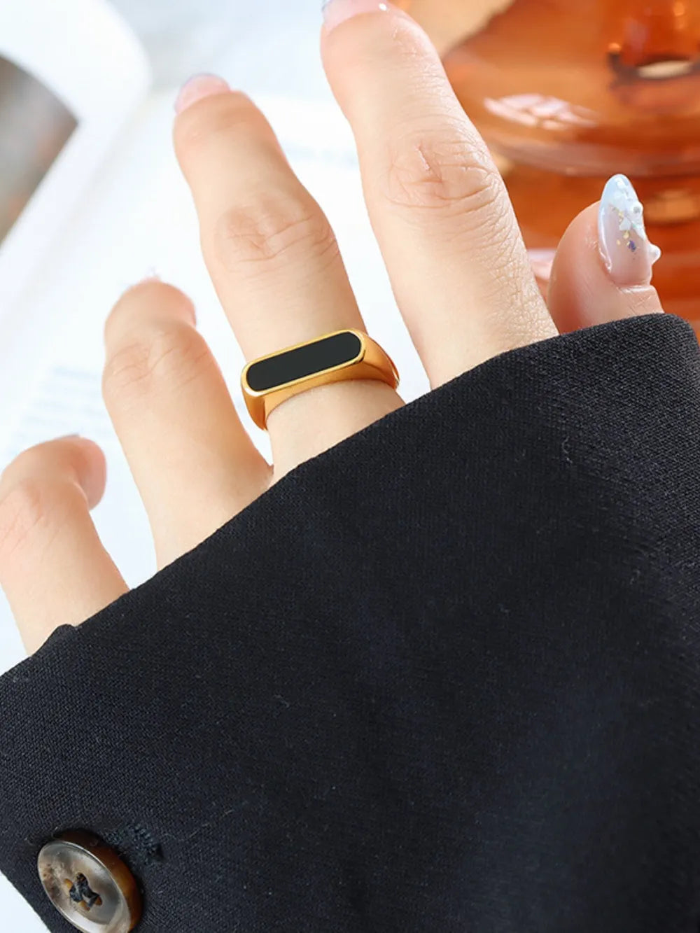 Gold rectangular signet ring with black enamel inlay detail.