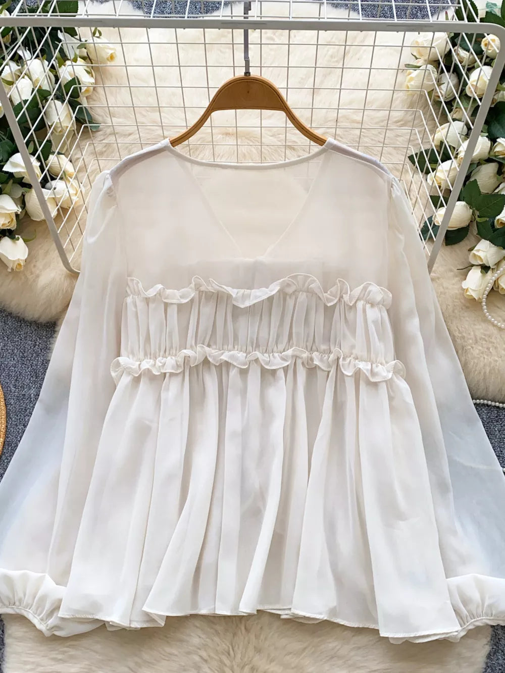 White chiffon blouse with ruffled V-neck and tie-front detail, long sleeves.