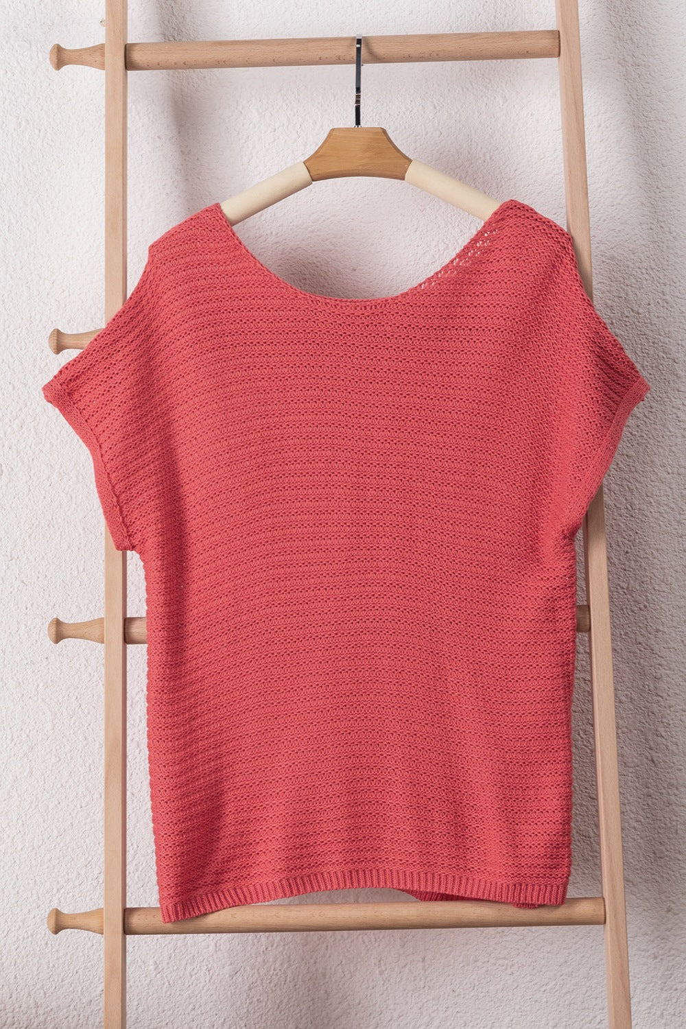 Open-knit dolman sleeve top in watermelon pink acrylic with a boat neckline.