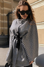 Houndstooth cape trench coat with black bow belt and high collar.