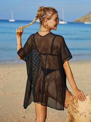 Black crochet beach cover-up with short sleeves and a relaxed fit, styled on a beach.