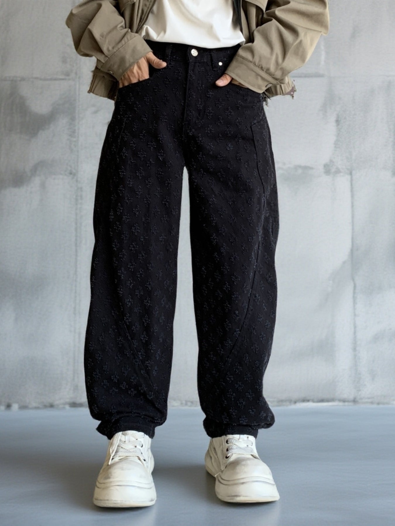 Men's black textured cotton wide-leg jeans with curved seams.