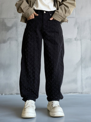 Men's black textured cotton wide-leg jeans with curved seams.