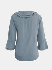 Light blue linen blouse with ruffled neckline and flared sleeves.