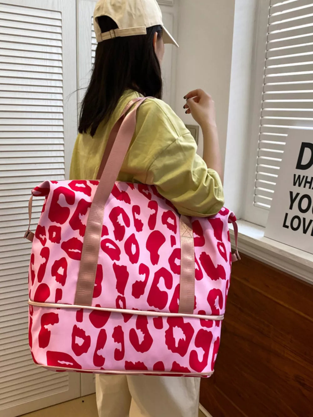 Vibrant pink travel bag with bold red leopard print and dual straps.