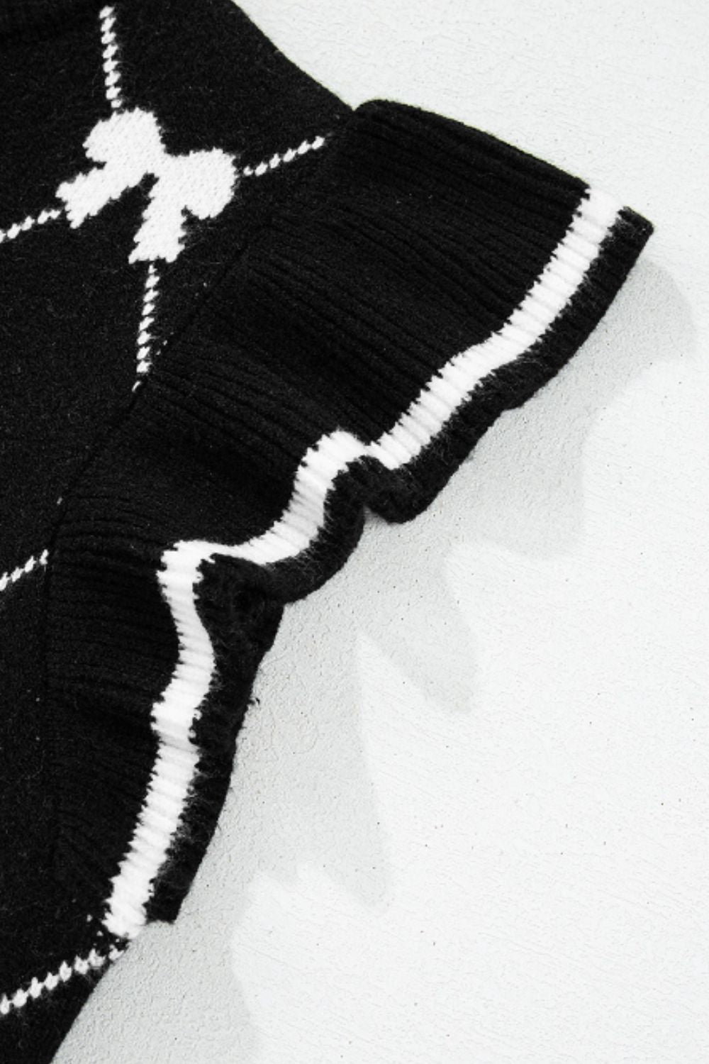 Black knit vest with white diamond bow pattern and striped trim