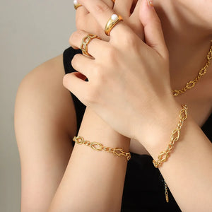Gold heart link chain bracelet with intricate knot details.