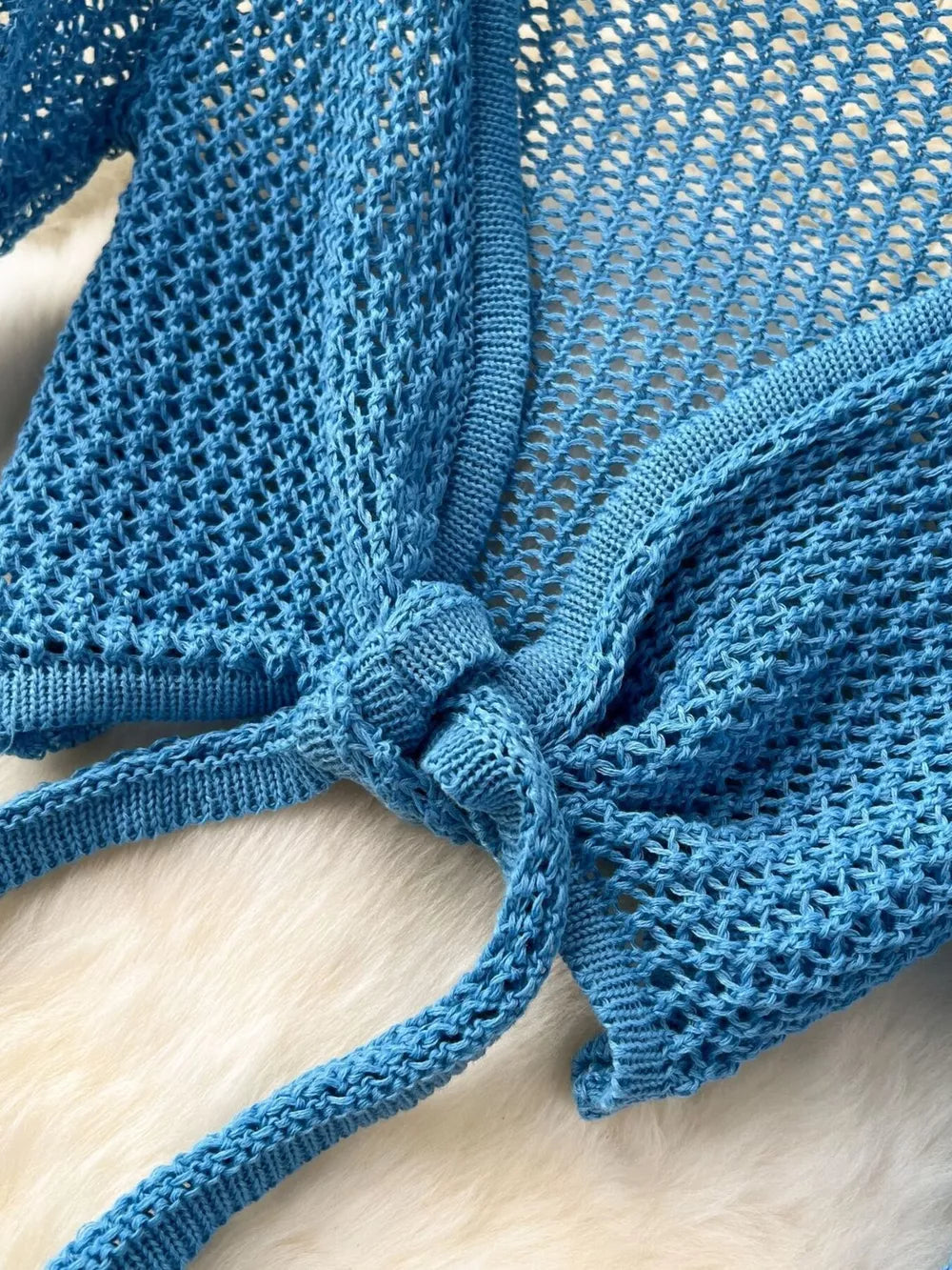 Blue knit tied crop top with open weave detail and tie closure.