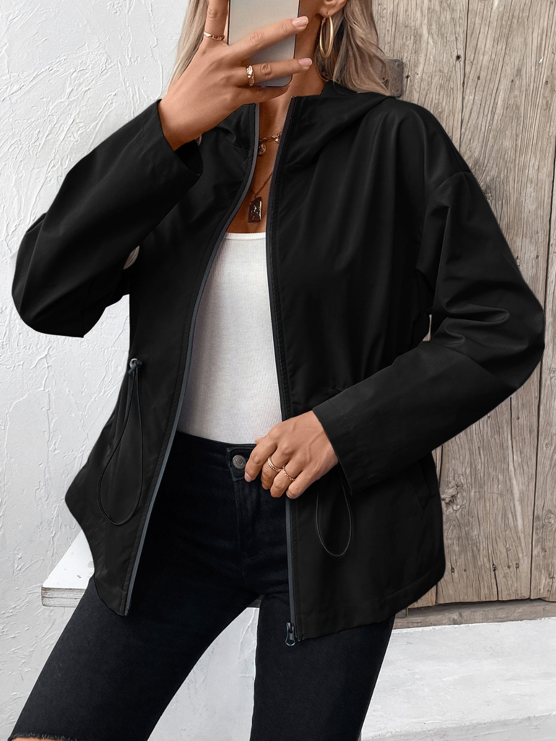 Black utility jacket with cinched waist, drawstring hood, and zip front.