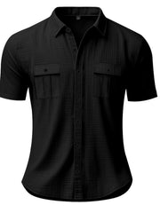 Black short sleeve button-down shirt with two chest pockets and a textured fabric.