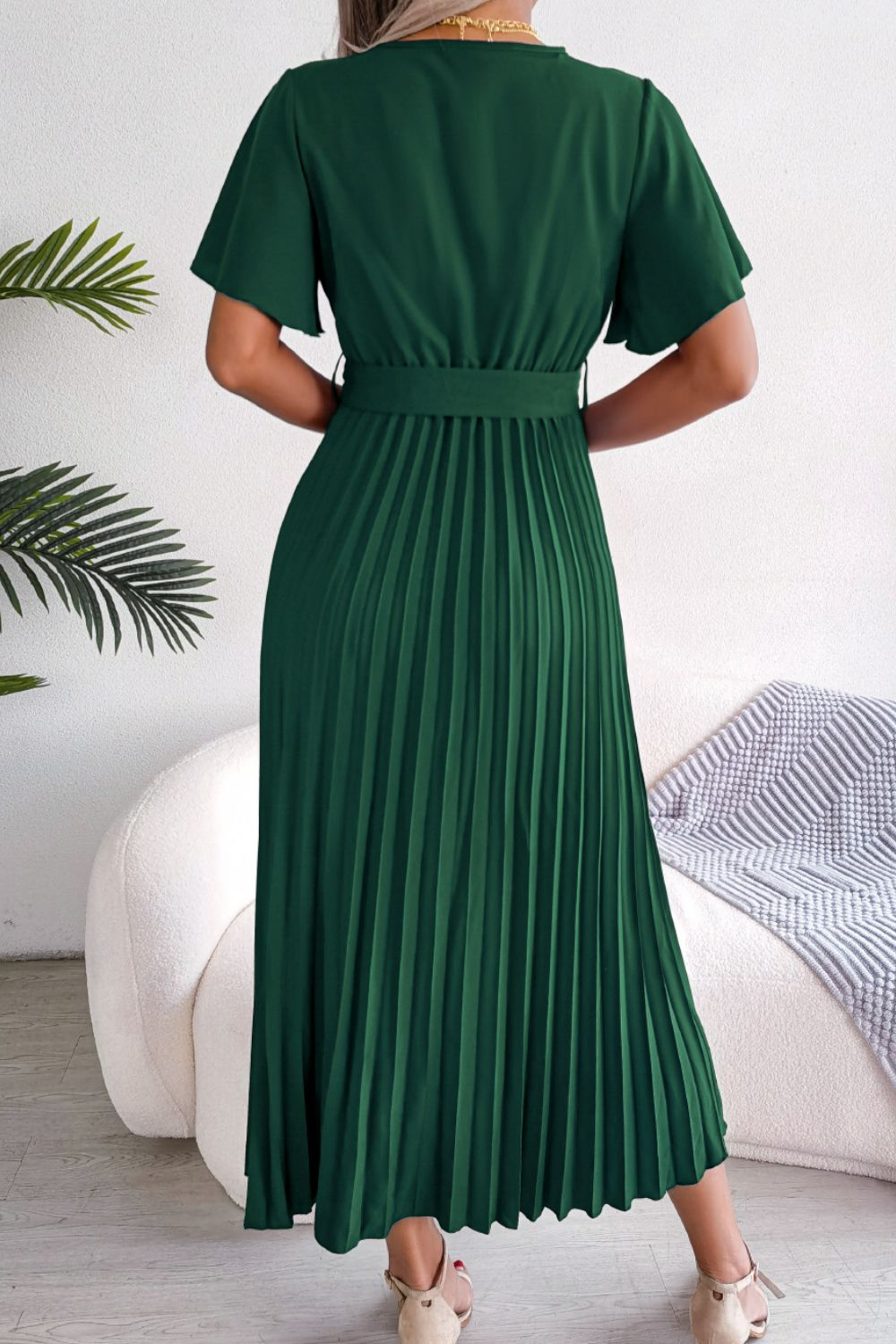 Green wrap bodice midi dress with flutter sleeves and pleated skirt.