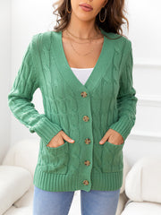 Green cable-knit cardigan with button front and patch pockets.