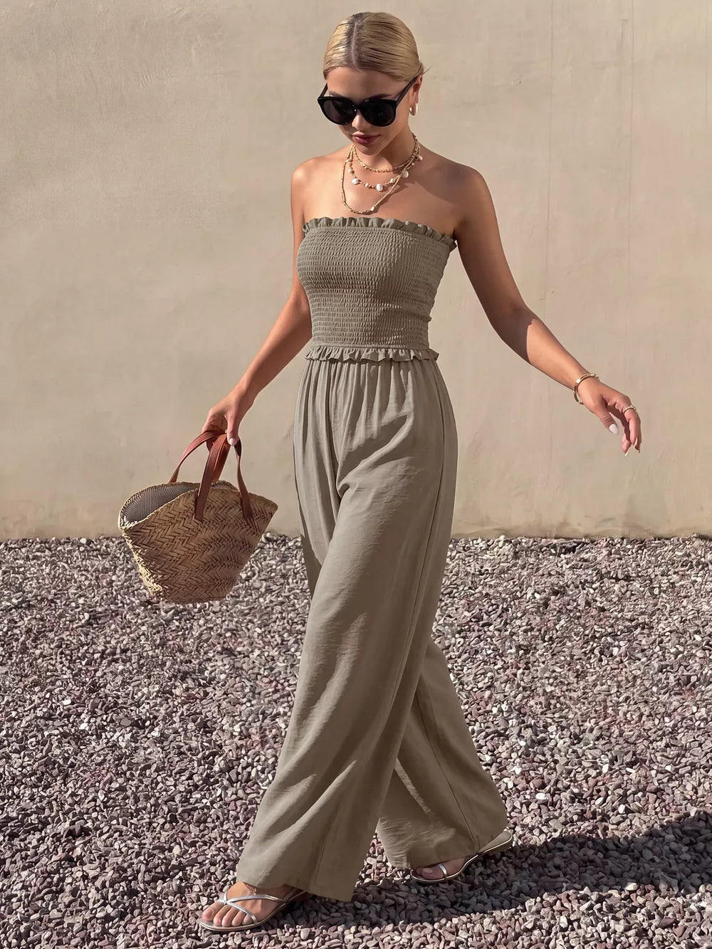 Smocked strapless wide-leg romper in olive green with frill detail.