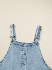 Tiered denim overall dress in light blue with button front and adjustable straps.