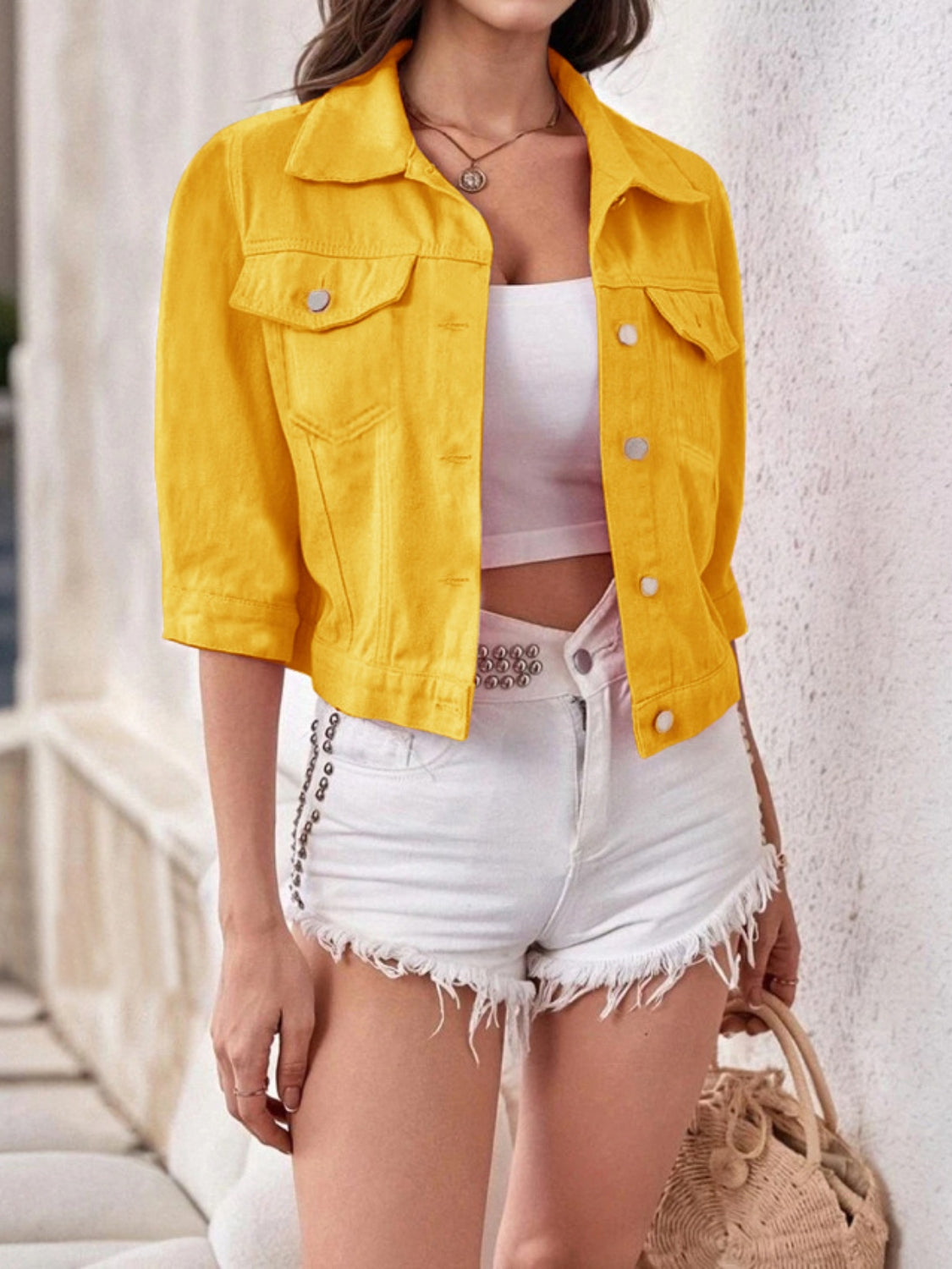Gold denim trucker jacket with cropped sleeves and button front, styled with white shorts.