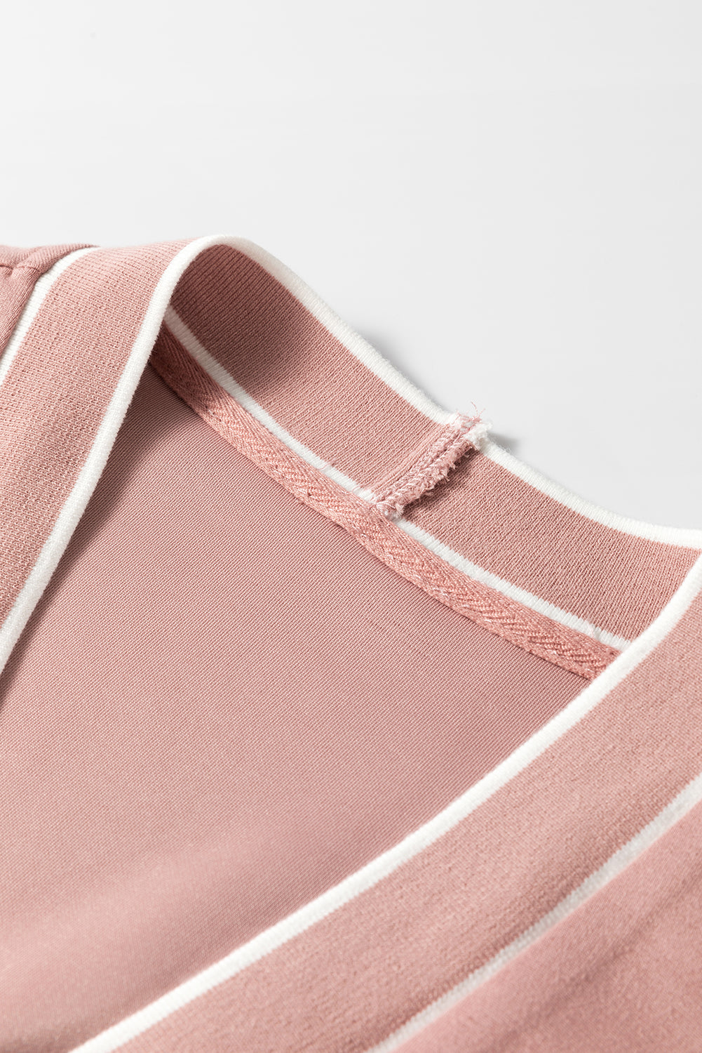 Dusty pink cardigan with white varsity trim detail at the neckline.