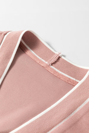 Dusty pink cardigan with white varsity trim detail at the neckline.