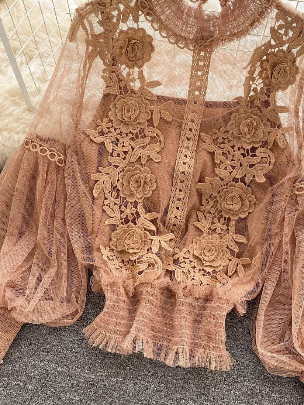 Light brown embroidered lace blouse with sheer sleeves and ruffled hem.