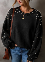 Black long sleeve sweater with pearl embellishments on sleeves and neckline, crew neck, casual knit.
