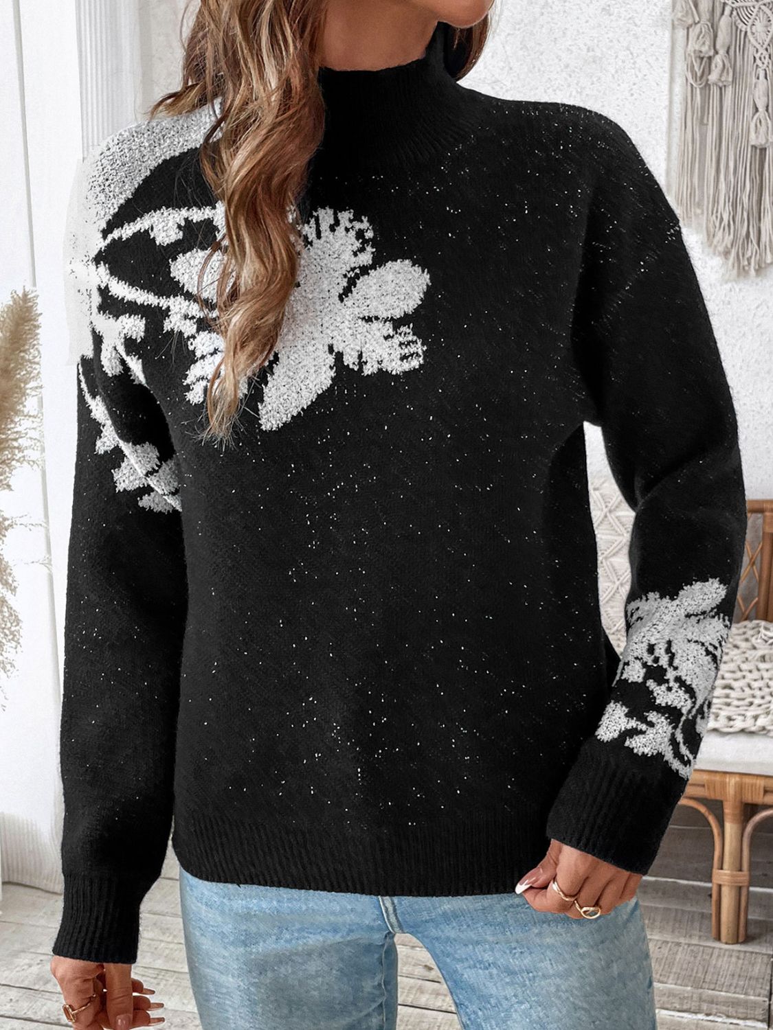 Black mock neck knit sweater with white floral embellishments and subtle sparkle detail.