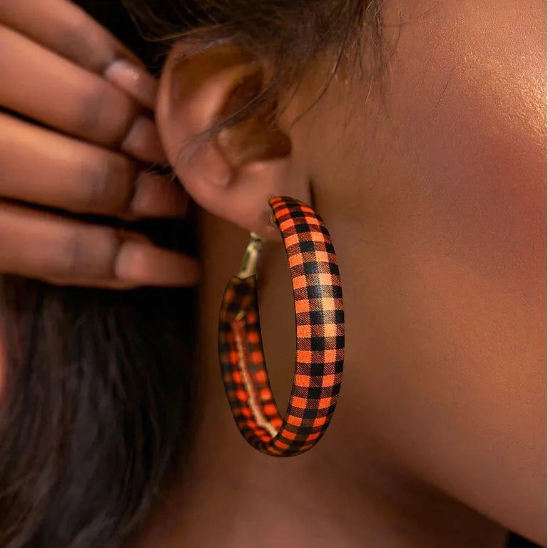 Orange buffalo check statement hoop earrings with black plaid pattern.