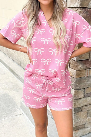 Pink ribbed loungewear set with white bow print, v-neck top and drawstring shorts.