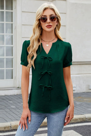 Dark green textured V-neck blouse with three bow details and short puff sleeves.
