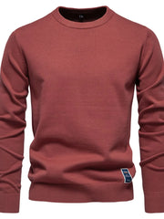 Rust crew neck knit sweater with ribbed cuffs and hem, featuring a small blue label detail.