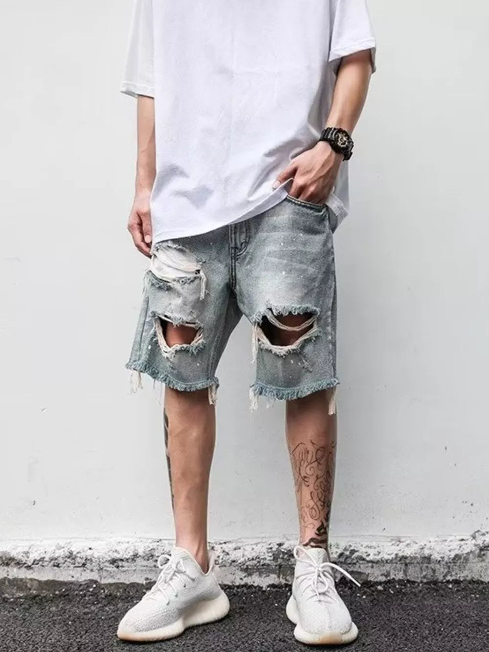 Men's light blue distressed denim shorts with rips and frayed hem.