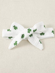 White cotton baby headband with green shamrock print and a bow detail.