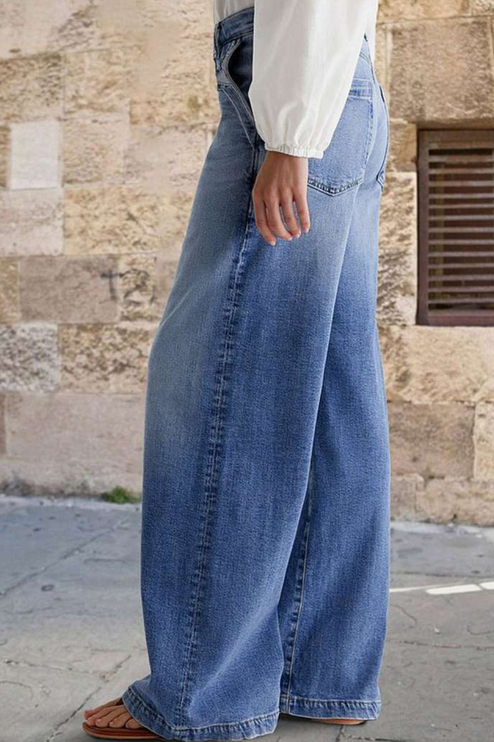 Light wash denim jeans with subtle stitching detail and a wide-leg cut.