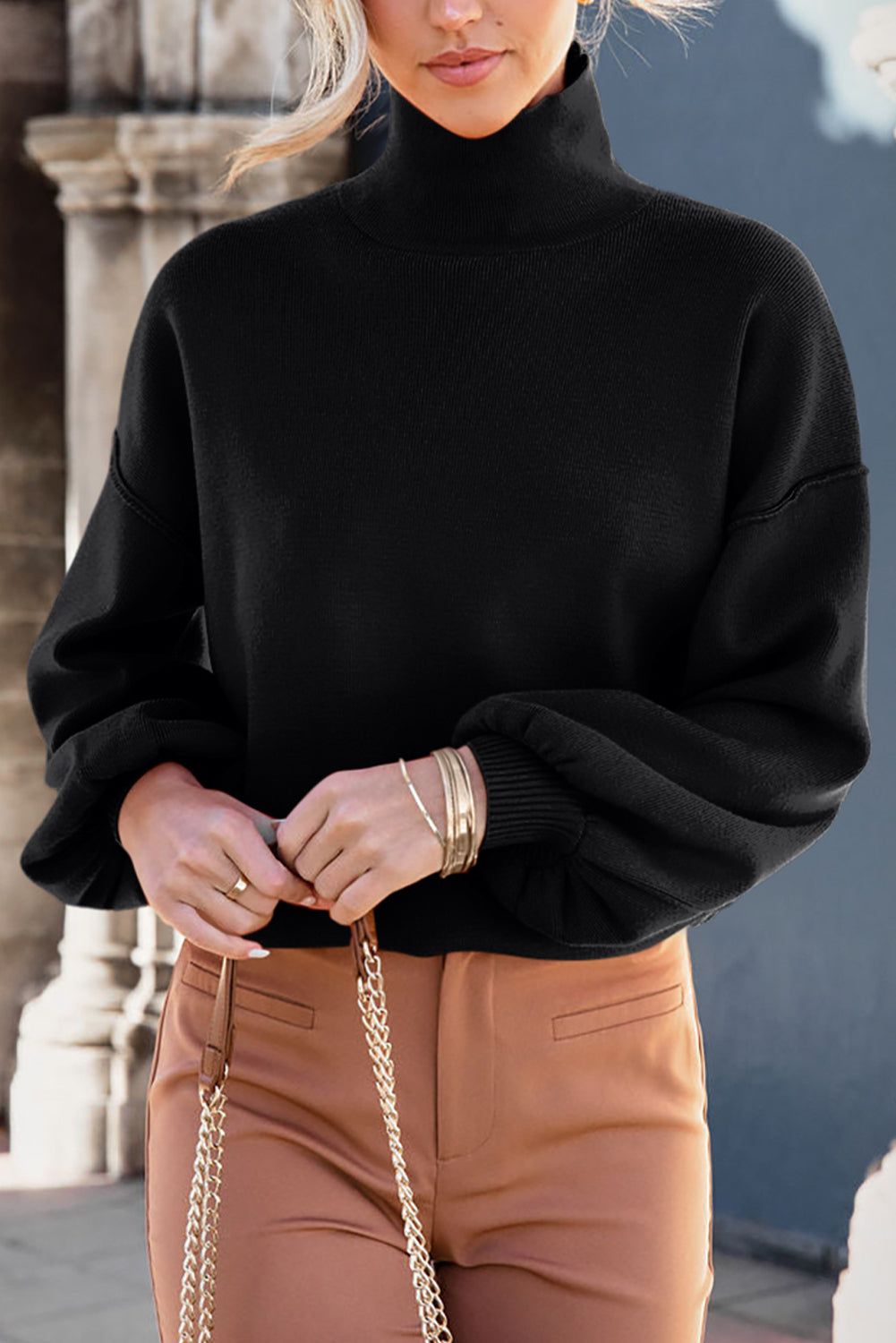 Black knit sweater with mock neck and balloon sleeves.
