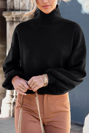 Black knit sweater with mock neck and balloon sleeves.