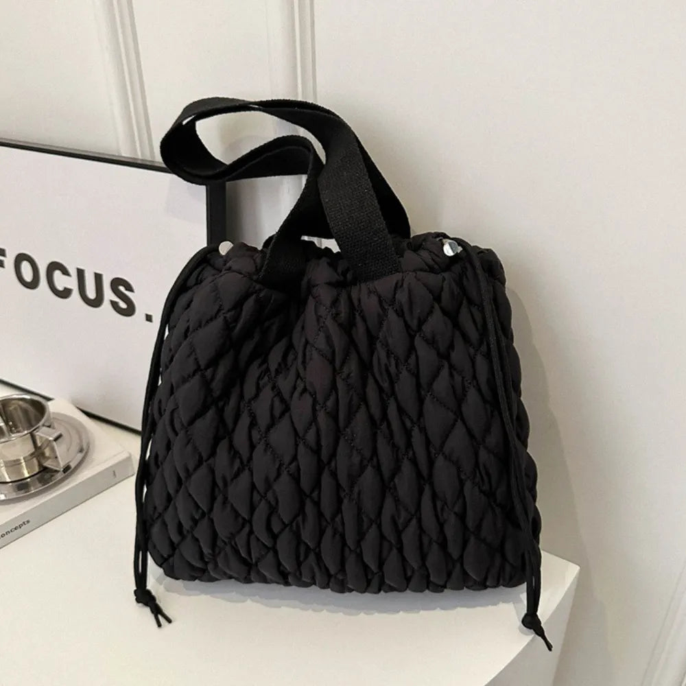 Black quilted drawstring carryall bag with diamond pattern and top handles.