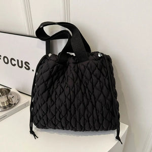 Black quilted drawstring carryall bag with diamond pattern and top handles.