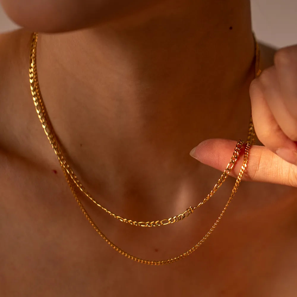 Gold dual-strand curb chain necklace with delicate links, styled on a woman's neck.